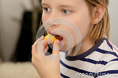 Nourishing bite: A young boy takes a nourishing bite of a juicy yellow plum, relishing the healthful fruit goodness Stock Photo