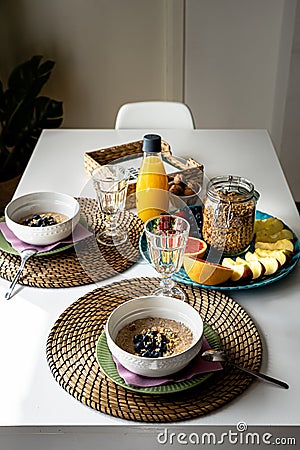 Nourishing fresh breakfast with porridge, fruits and orange juice on a table indoor. Substantial meal with oatmeal and fruits Stock Photo