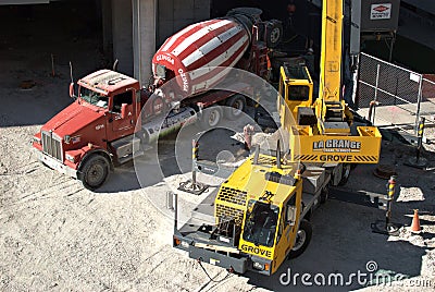 A cement truck and a crane work together to deliver material to higher levels. Editorial Stock Photo