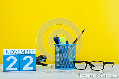 November 22nd. Day 22 of month, wooden color calendar on yellow background with office supplies. Autumn time Stock Photo