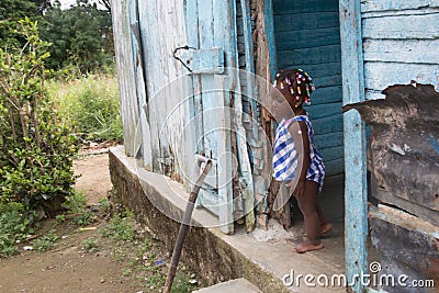 Dramatic image of small Haitian child standing in her doorway of their home looking for her mother. Editorial Stock Photo