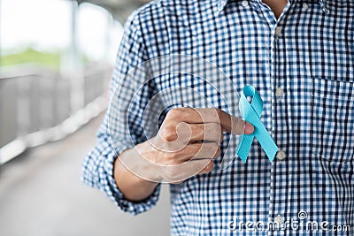 November Prostate Cancer Awareness month, Man in blue shirt with hand holding Blue Ribbon for supporting people living and illness Stock Photo