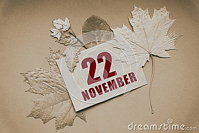 november 22. 22th day of month, calendar date.Envelope with the date and month, surrounded by autumn leaves on brown Stock Photo