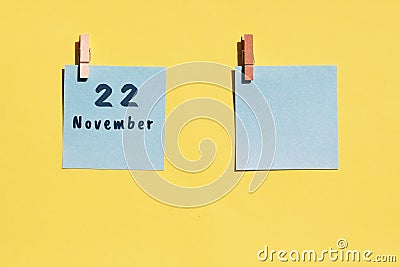 22 november. 22th day of the month, calendar date. Two blue sheets for writing on a yellow background. Top view, copy space. Stock Photo