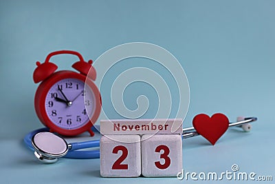 November 23th. White wooden blocks of the calendar with the date, clock and stethoscope on a blue pastel background. Selective Stock Photo