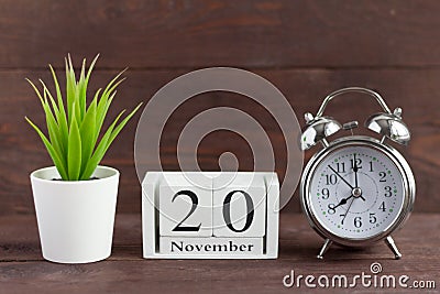 November 20 on a white wooden calendar next to an alarm clock on a dark wooden background Stock Photo