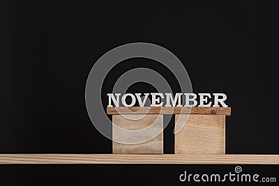 November by wooden letters. Black background. Front view. Autumn calendar. Copy space Stock Photo