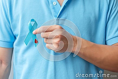 November World Diabetes day Awareness month, man holding light Blue Ribbon with blood drop shape for supporting people living, Stock Photo