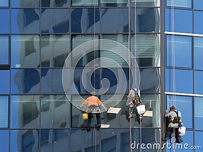 Three workers cleaning the glass building`s windows Editorial Stock Photo
