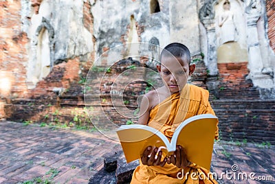 Novice monk reading outdoors Stock Photo