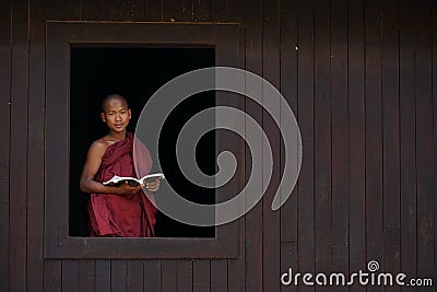 Novice monk smiles at the old temple window Editorial Stock Photo