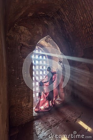 Novice monk standing in ancient temple Stock Photo
