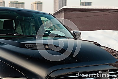 Black Dodge Ram with an engine of 5.7 liters hood with ventilation holes view on the car parking with snow background Editorial Stock Photo