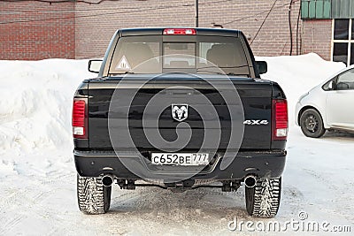 Black Dodge Ram with an engine of 5.7 liters rear view with two exhaust pipes on the car parking with snow background Editorial Stock Photo