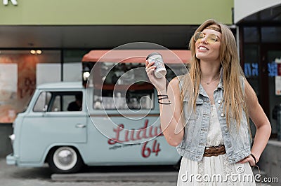 Novosibirsk, Russia - July 20, 2020: A hippie woman drinks coffee on the background of a camper. Classic Volkswagen van Editorial Stock Photo