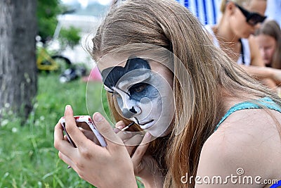 NOVOSIBIRSK, RUSSIA - JUNE 26, 2016: Girl draws paints on his face muzzle pet Editorial Stock Photo