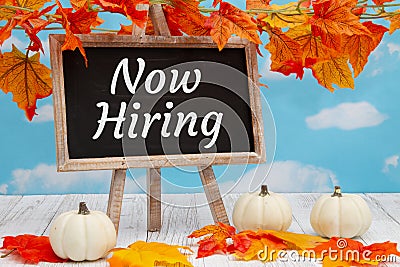 Now hiring sign with standing chalkboard with fall leaves with pumpkins Stock Photo
