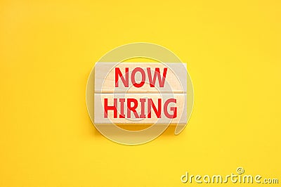 Now hiring symbol. Concept words Now hiring on beautiful wooden block. Beautiful yellow table yellow background. Business Stock Photo