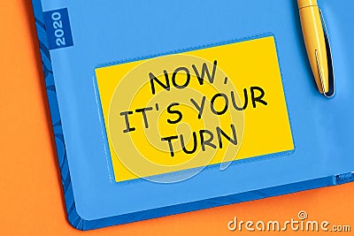 NOW ITS YOUR TURN the word is written in black letters on the yellow paper for notes Stock Photo