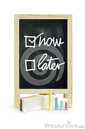 Now or Later with checkboxes - white chalk handwriting on blackboard Clipping path. Stock Photo