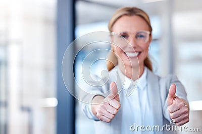 Now thats what Im talking about. Portrait of a mature businesswoman showing thumbs up in a modern office. Stock Photo