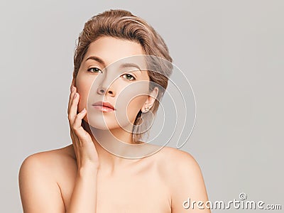 Nude make-up on a beautiful blonde model. Shot in a studio on a light background. Retouched skin. Copy space for text Stock Photo