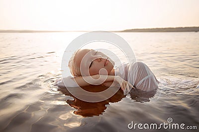 Nude naked sexy woman in water at sunset. Beautiful blonde woman with short wet hair and big breasts, art portrait in sea Stock Photo