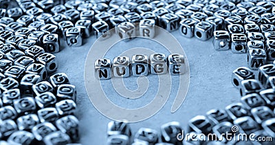 Nudge - Word from Metal Blocks on Paper Stock Photo