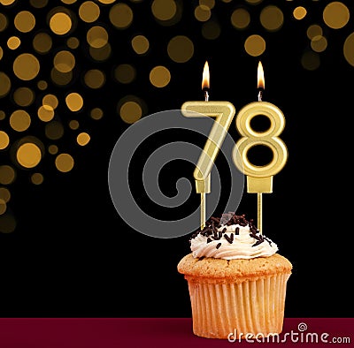 Number 78 birthday candle - Cupcake on black background with out of focus lights Stock Photo