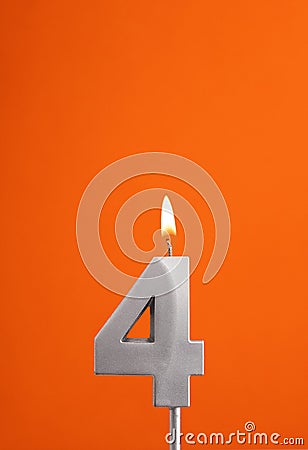 Number 4 - Burning anniversary candle on orange foamy background Stock Photo