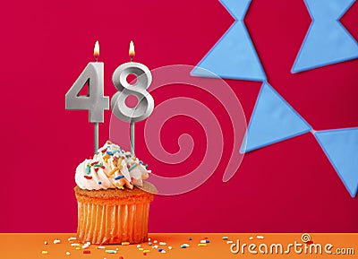 Number 48 candle with birthday cupcake on a red background with blue pennants Stock Photo