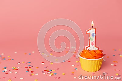 Number 1 candle in a cupcake against a pastel pink background. First bithday cake. Copy space Stock Photo