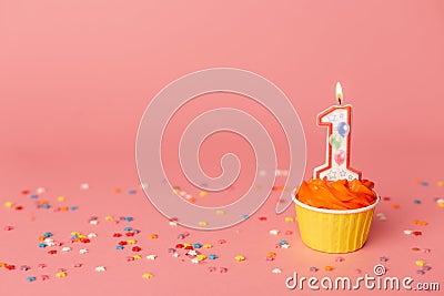 Number 1 candle in a cupcake against a pastel pink background. First bithday cake. Copy space Stock Photo