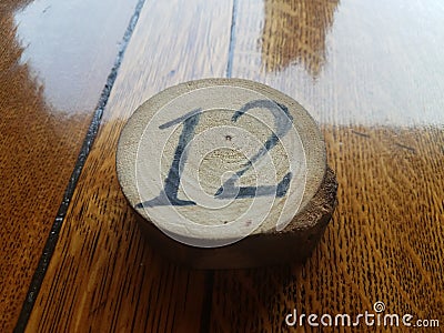 The number 12 on a circular piece of wood on a waxed wooden table Stock Photo