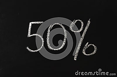 Number fifty percent written in white chalk on a black chalkboard. 50 Stock Photo