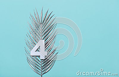 Number four shape with silver palm leaves on blue background. Summer concept. Flat lay. Top view Stock Photo