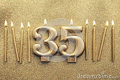 Number 35 gold celebration candle on a glitter background Stock Photo