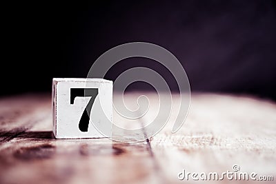 Number 7 isolated on dark background- 3D number seven isolated on vintage wooden table Stock Photo