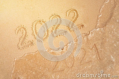 number of the new year written in sand, on tropical beach. Change numbers 2021 to 2022. New year holidays on a tropical island. Stock Photo