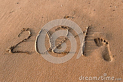 Number 2021 is written on the sand at sea.. Two thousand twenty one.a footprint in the sand Stock Photo