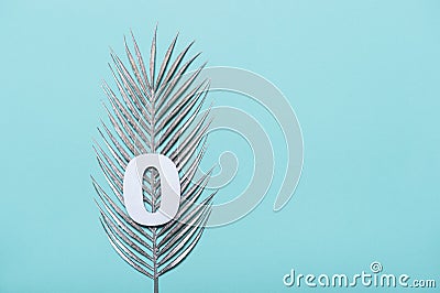 Number zero shape with silver palm leaves on blue background. Summer concept. Flat lay. Top view Stock Photo