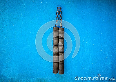 Nunchaku weapon isolated on Blue background. Black nunchaku training for beginner. Hot Tactical Gear Martial Arts Equipments Stock Photo