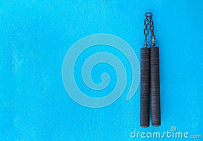 Nunchaku weapon isolated on Blue background. Black nunchaku training for beginner. Hot Tactical Gear Martial Arts Equipments Stock Photo