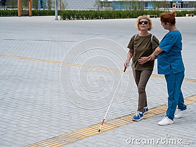 A nurse accompanies an elderly blind woman on a walk. Stock Photo