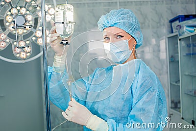 Nurse adjusting infusion bottle with against Stock Photo