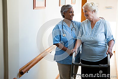 Nurse assisting patient in walking with walker at retirement home Stock Photo