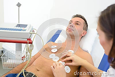 Nurse attaching heart monitor pads to man`s chest Stock Photo