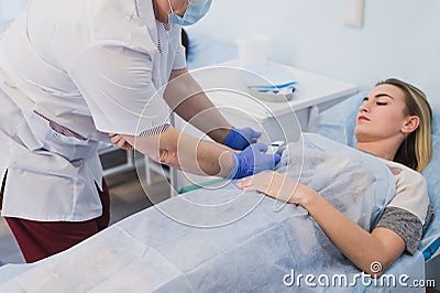 Nurse attaching intravenous tube to patient`s hand in hospital bed Stock Photo