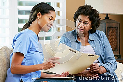 Nurse Discussing Records With Senior Female Patient During Home Stock Photo