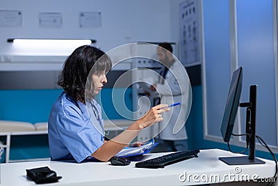 Nurse doing overtime work with computer and checkup files Stock Photo